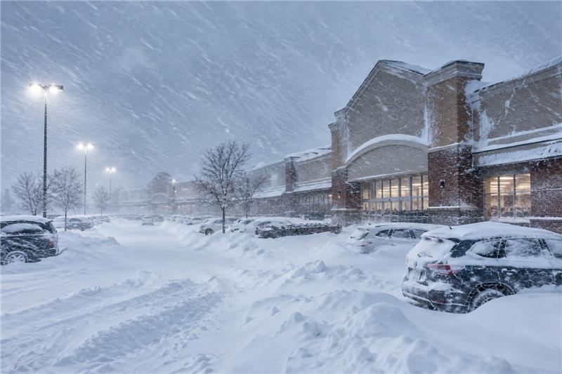 Grocery storefront and parking lot buried in snow during a winter storm